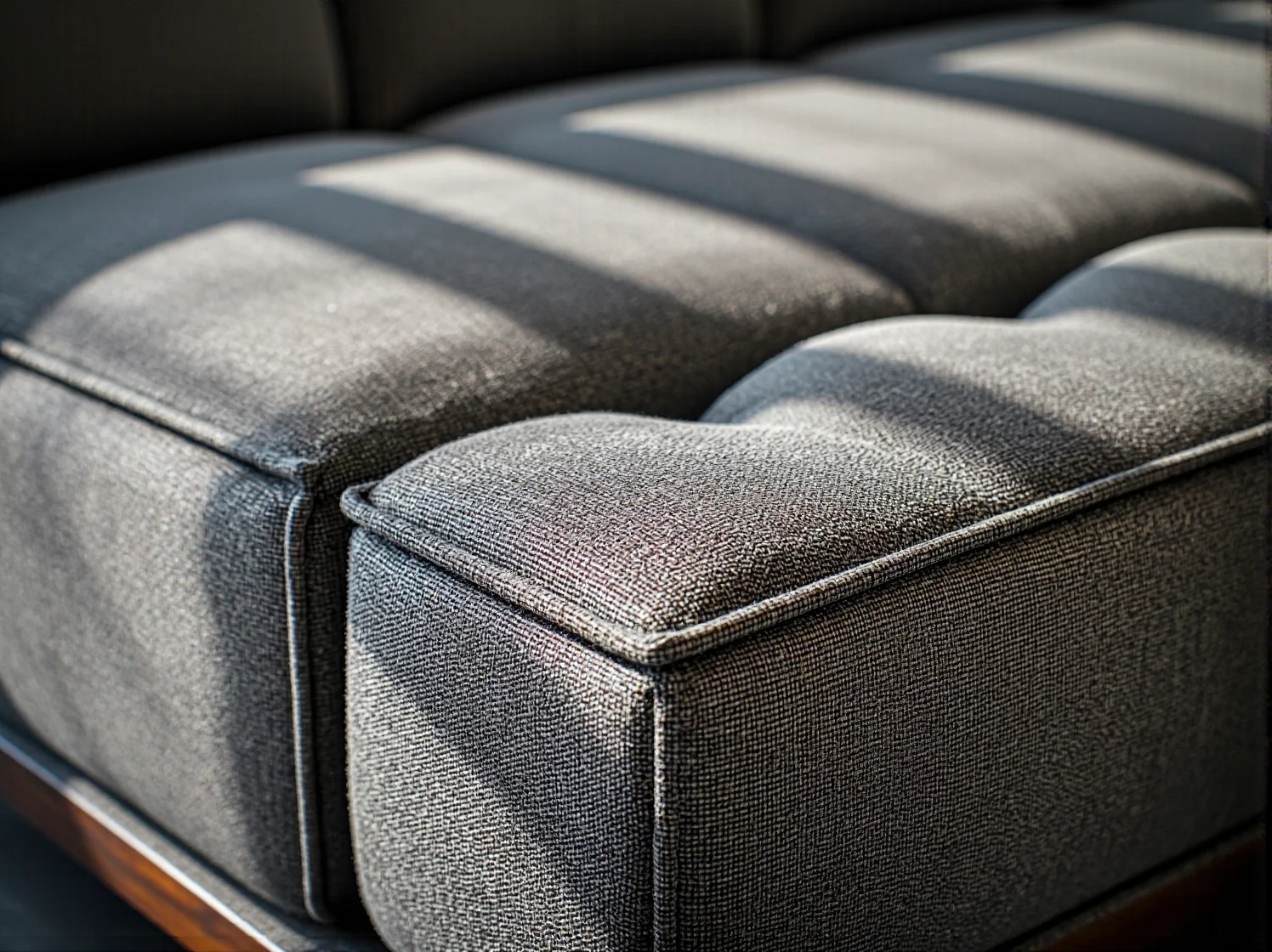 Grafitowa sofa tapicerowana z pikowanym siedziskiem i drewnianą podstawą