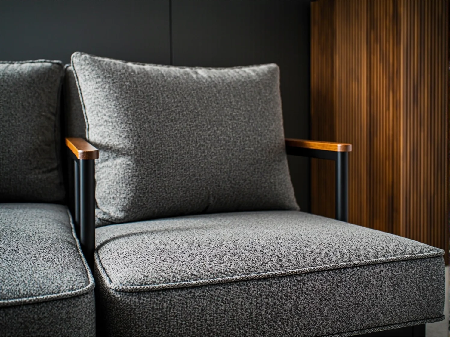 Szary fotel tapicerowany z drewnianymi podłokietnikami i metalową ramą