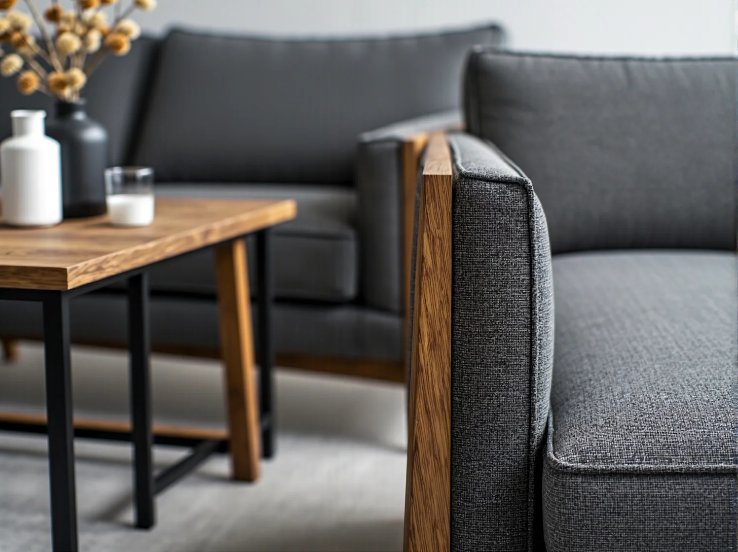 Szara sofa tapicerowana z drewnianymi podłokietnikami dębowymi