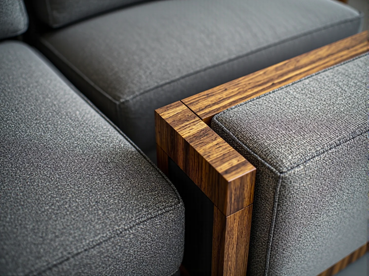 Szara sofa tapicerowana z drewnianym podłokietnikiem orzechowym